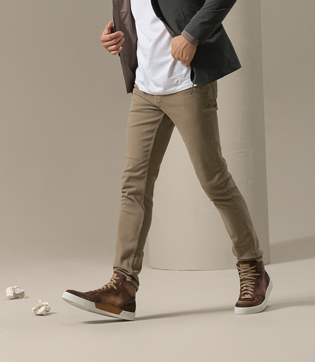 A male model casually strolls in white shirt, green jacket, khaki pants, and Magnanni’s Rubio Torba fashion sneaker.