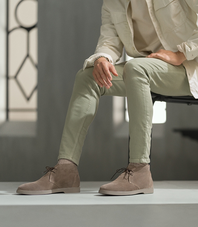 Seated male model in white jacket and light olive pants wearing the Duran in Taupe.