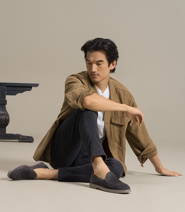 Seated male model leaning on left hand styled in tan shacket and dark gray pants wearing the Magnanni Danil dress shoe in Grey.