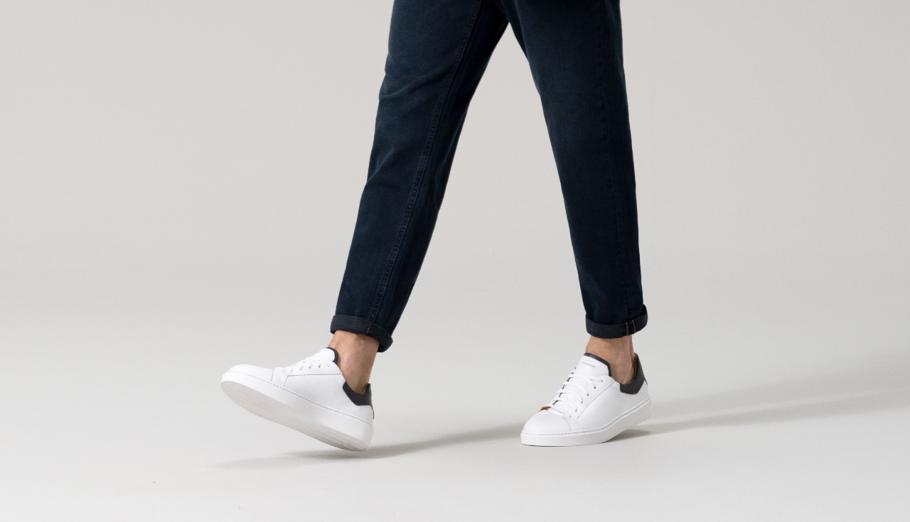 Close up of a man stepping forward in dark blue jeans and Magnanni Castillo II sneakers.