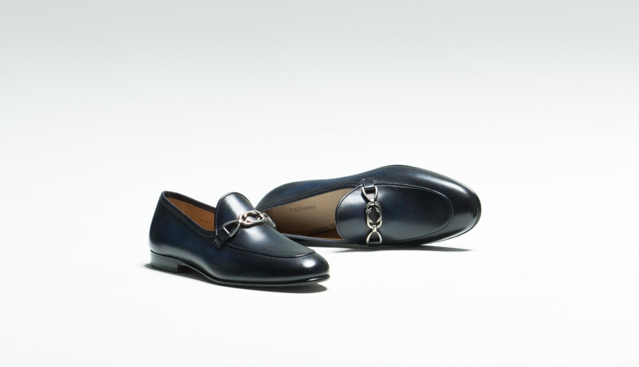 A pair of the Mina Navy loafer sit in an empty white room.