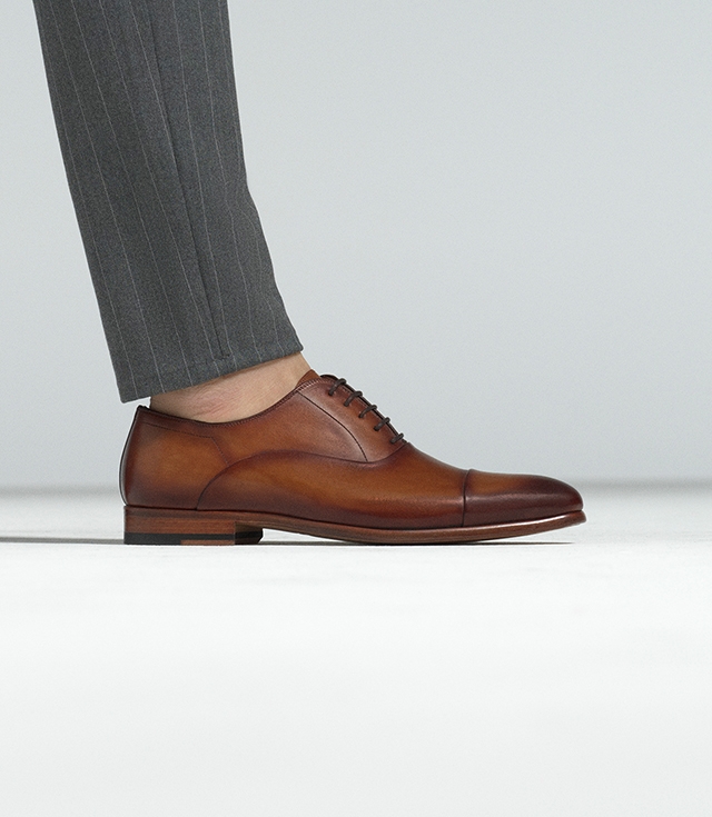 Close up of a male model in dark grey pinstripe pants as he wears Magnanni Segovia dress shoes in Curri.