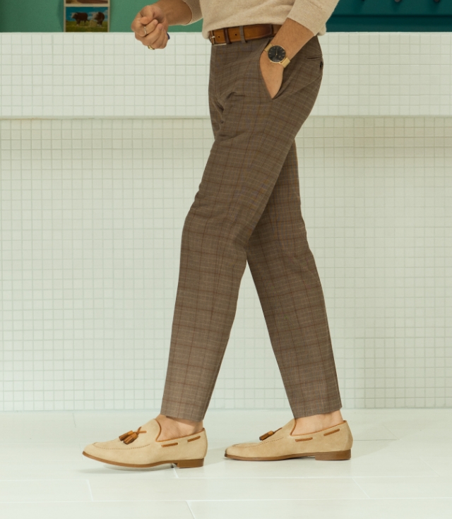 A model steps forward, wearing plaid grey pants and Magnanni Delrey II loafers in Cream Suede.