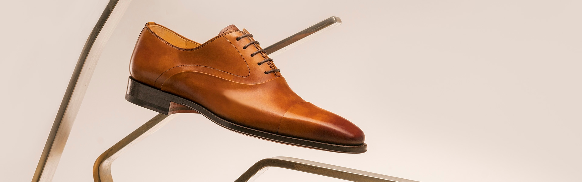 The Magnanni Saffron lace up sits on an angular, golden display.