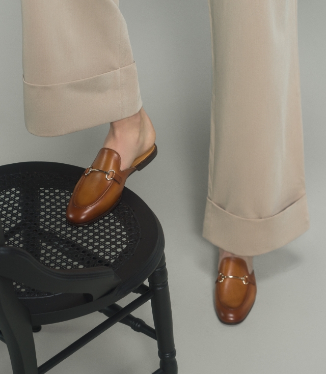 A woman steps on a chair in her Magnanni Stella V Cognac loafers.