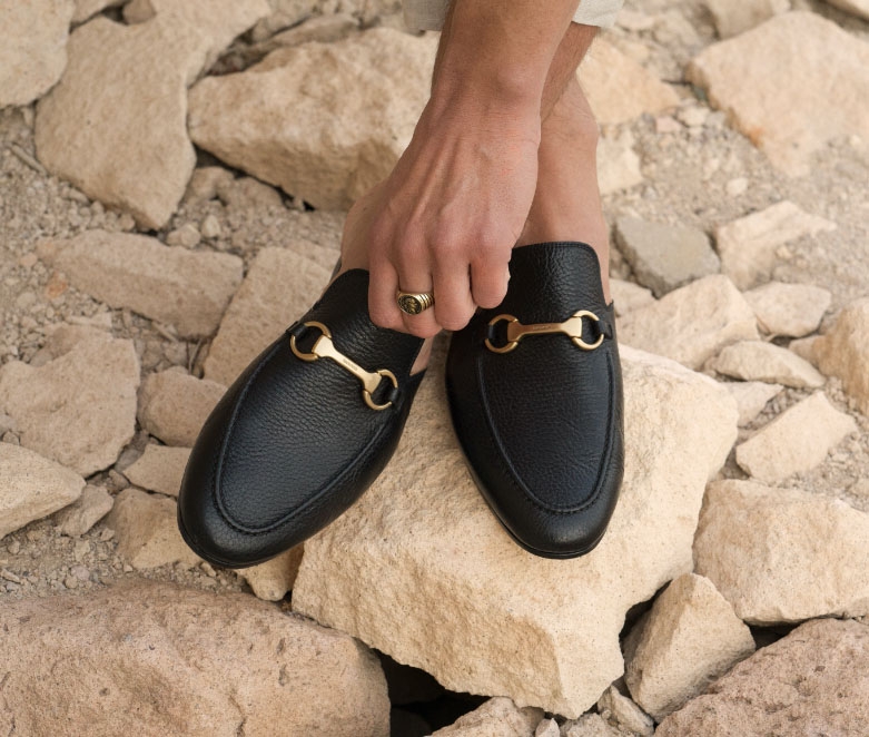 Pachino Black shoes sit on some large rocks.