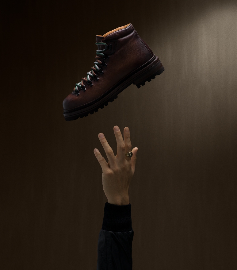 A male model reaches for a floating Magnanni Montana III Mid-brown boot.